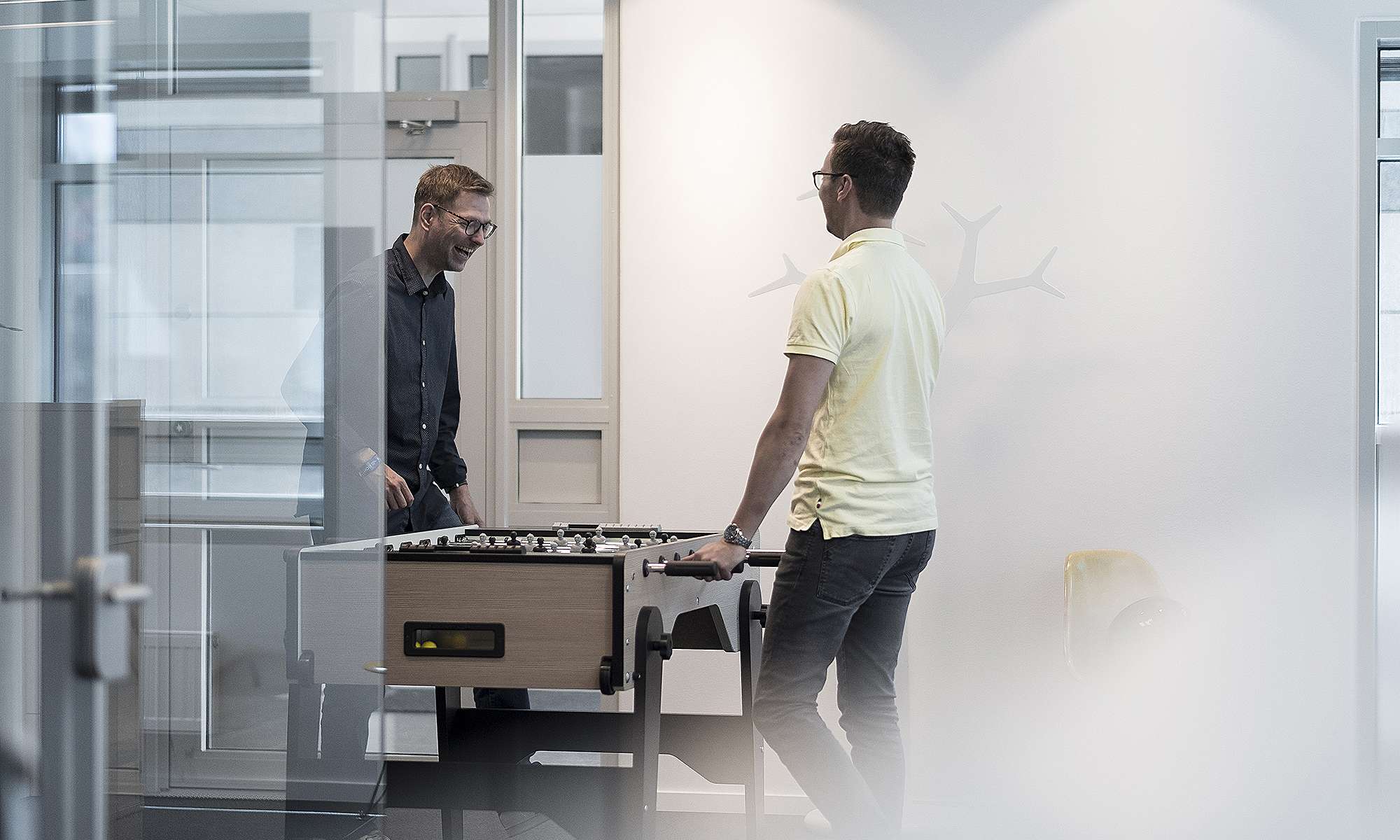 Bilde av to ansatte i godt humør som kobler av med å spille foosball