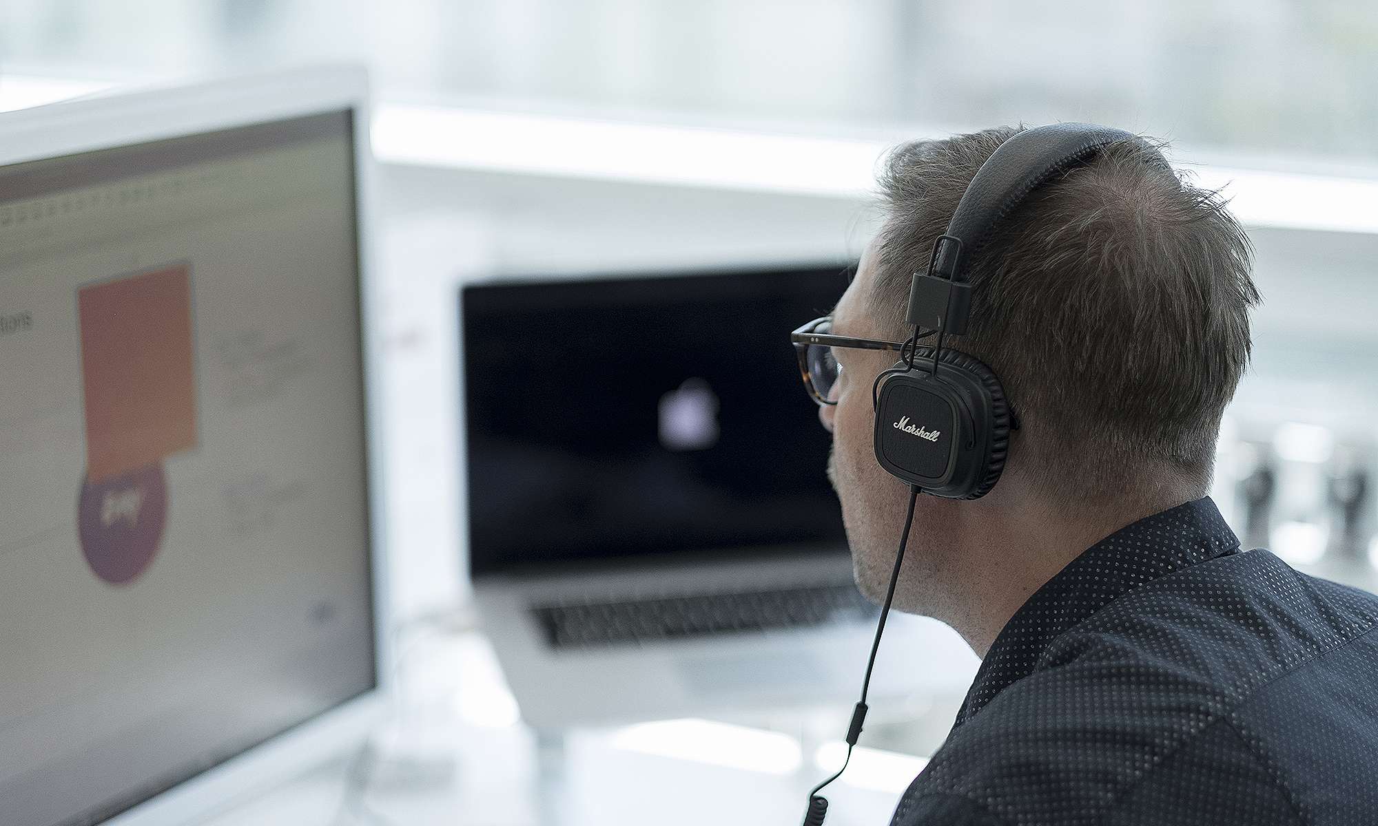 Bilde av grafisk designer foran to skjermer